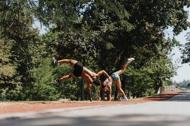 Aktywna para ciesząca się treningiem na świeżym powietrzu i praktyką Cartwheel w Sunny Park - Zdjęcie, obraz