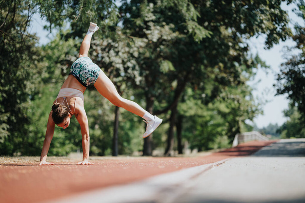 Sport actif Femme performant Cartwheel dans le parc par une journée ensoleillée - Photo, image