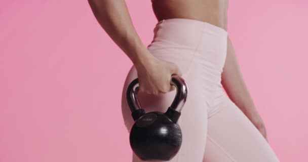 Strong, kettlebell and woman with fitness, exercise and model on pink studio background. Mockup space, person and bodybuilder with equipment, endurance and progress with wellness, training and health. - Footage, Video