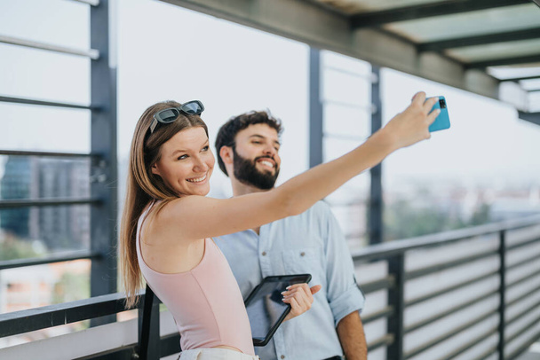 Young, beautiful, business couple taking a break from work in the city. They are taking a selfie. - Photo, Image