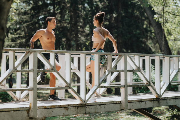 Junges Paar trainiert zusammen im Freien und macht Liegestütze auf einer Brücke im Park. Fit und motiviert üben sie anspruchsvolle körperliche Aktivitäten in natürlicher Umgebung aus und inspirieren zu einem gesunden Lebensstil. - Foto, Bild