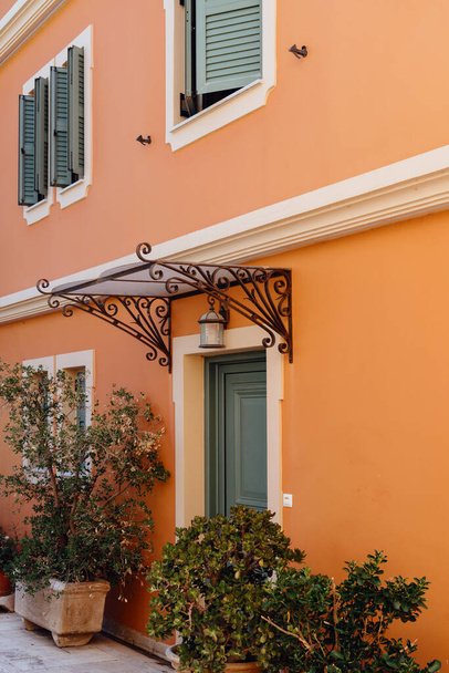 La cálida fachada de una casa mediterránea con persianas verdes y plantas en maceta crea una entrada atractiva - Foto, Imagen