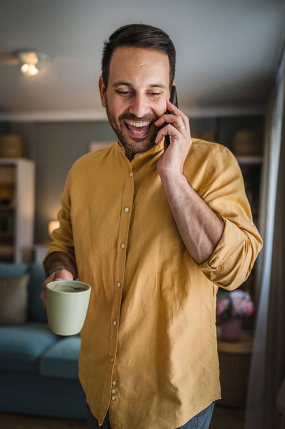Jeden mężczyzna dorosły biały mężczyzna używać telefon komórkowy smartfon do rozmowy rozmowy szczęśliwy uśmiech w domu nosić koszulę i okulary prawdziwa osoba kopiować przestrzeń - Zdjęcie, obraz