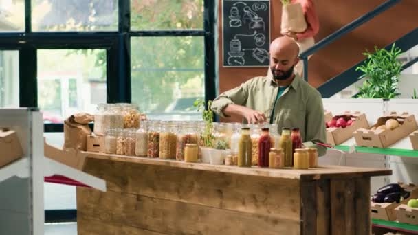 Orta Doğulu bir adam ekolojik gıda dükkanında organik meyve ve sebzeleri inceliyor, sürdürülebilir makarna veya baharatla kavanozlar açıyor. Müşteri yeni biyo-mallara hayran.. - Video, Çekim