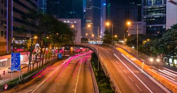 Traffico stradale a Hong Kong durante la notte. Edifici per uffici grattacieli e trafficato traffico su strada con auto sfocate sentieri leggeri. Hong Kong, Cina. Effetto zoom out fotocamera - Filmati, video