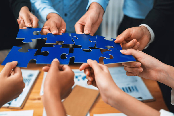 Multiethnische Geschäftsleute halten Puzzleteile zusammen und verbinden sie als effektive Lösung zur Lösung von Teamarbeit, gemeinsamer Vision und gemeinsamem Ziel, das unterschiedliche Talente vereint. Akribisch - Foto, Bild