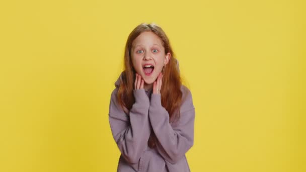 Oh my God, Wow. Young preteen child girl kid looking surprised at camera with big eyes, shocked by sudden victory game winning lottery goal achievemen good news. Children isolated on yellow background - Footage, Video
