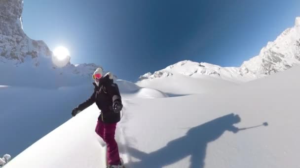 СЕЛЬФИЕ, ЛИНС: Счастливая женщина наслаждается сноубордом нетронутой снежной террасой во время приключенческой прогулки на вертолете в красивых Албанских Альпах. Она весело ездит верхом и распыляет облака свежего снега. - Кадры, видео