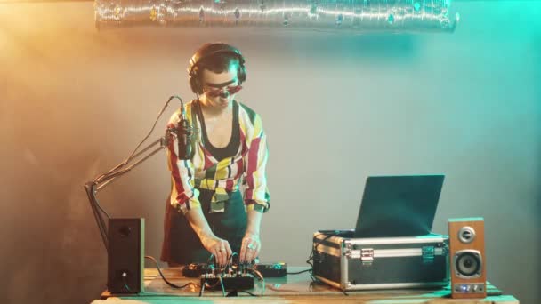 Woman DJ stuurt luchtkusjes van het clubpodium, en stuurt liefde naar haar fans na het mixen van geweldige techno-platen. Jonge performer creëert nieuwe nummers met draaitafels en schijven. Driepoot schot. - Video