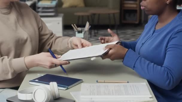 Recorte de la secretaria negra dando titular de documento a la mujer de negocios con silla de ruedas para firmar durante la jornada laboral en la oficina moderna - Metraje, vídeo