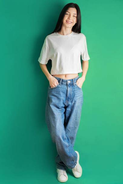 Портрет молодой девушки-подростка в белой футболке и джинсах. - Фото, изображение
