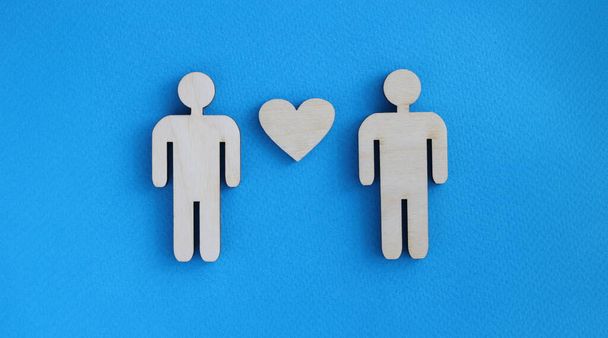 Wooden toy men and heart lying on blue background. Love between men concept - Photo, Image