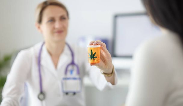 Docteur tenant un pot de pilules de marijuana en gros plan. Concept de traitement de la toxicomanie - Photo, image