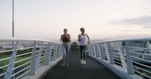 Woman, running or exercise on bridge together, strong or fitness collaboration in city for training. Young people, friends or commitment in sport challenge, health or cardio workout in urban outdoor. - Footage, Video
