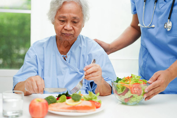 Aziatische voedingsdeskundige met gezond voedsel voor de patiënt in het ziekenhuis, voeding en vitamine. - Foto, afbeelding