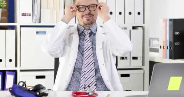 Porträt eines lächelnden Arztes mit Brille am Arbeitsplatz. Die Wahl eines ärztlichen Konzepts - Filmmaterial, Video