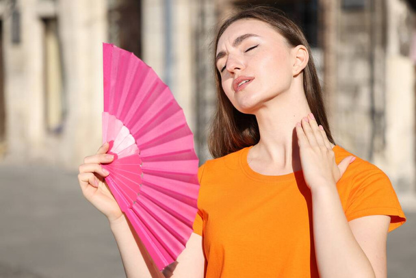 Woman with hand fan suffering from heat outdoors - Fotó, kép