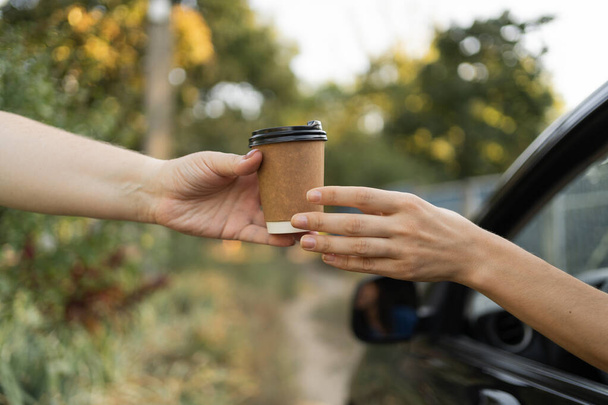 Motorista feminina comprando uma xícara de café quente enquanto dirige o veículo. Café Takeaway antes da sua viagem. Espaço de cópia - Foto, Imagem