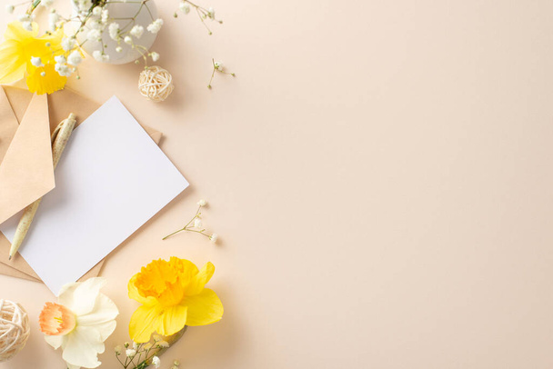 Share beauty of spring holidays with narcissus and gypsophila. From above, observe flower branches, an envelope and empty paper on a beige isolated background, suitable for adverts or text messages - Photo, Image