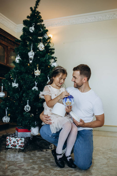 padre e hija están sentados cerca del árbol de Navidad en casa - Foto, imagen