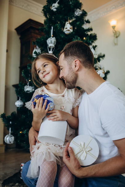 father and daughter are sitting near the Christmas tree at home - Photo, Image