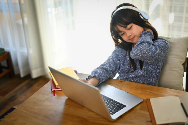 Evde dizüstü bilgisayarda çalışan yorgun ve sıkılmış bir kız öğrenci. Çevrimiçi eğitim kavramı - Fotoğraf, Görsel