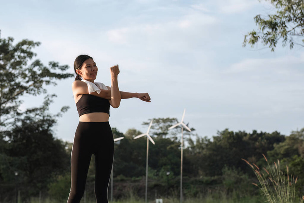 Hermosa mujer asiática en ropa deportiva que se extiende antes de correr o trotar en el parque. Para cuidar de su salud y ser fuerte. - Foto, imagen