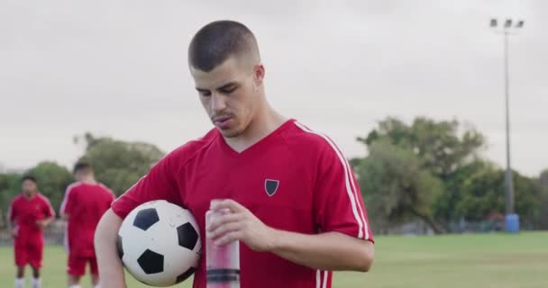 Soccer, ball and player drink water on field for game, practice match and competition outdoors. Sports, hydration and thirsty person with bottle for wellness in training, fitness and exercise. - Footage, Video