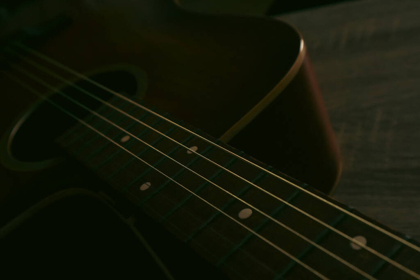 Primer plano de una cuerda de guitarra acústica y diapasón con nuevas cuerdas. Foto de una vieja guitarra de madera con cuerdas de acero. Cuerdas de cerca. - Foto, Imagen