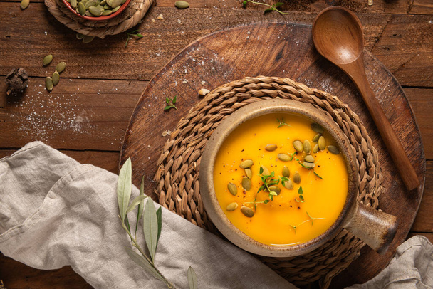 Смачний гарбузовий вершковий суп з органічними травами та гарбузовим насінням у старовинній керамічній мисці. Осінь концепція затишної вечері - Фото, зображення
