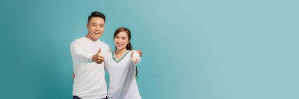 Photo of happy excited young loving couple standing isolated, showing thumbs up gesture. - Photo, Image
