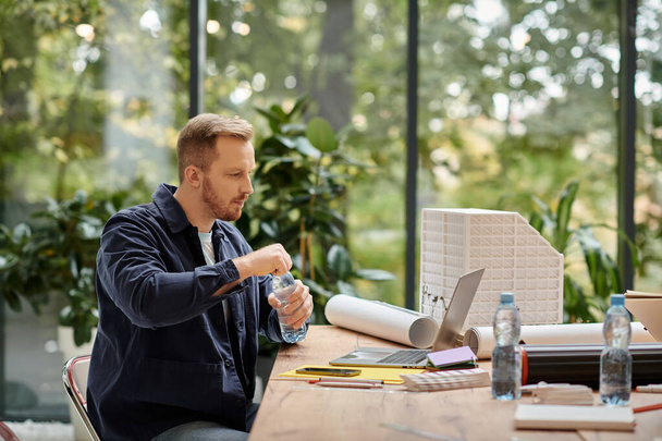 добре виглядає зосереджений чоловік в повсякденному вбранні, що працює на своєму стартапі з ноутбуком в офісі - Фото, зображення
