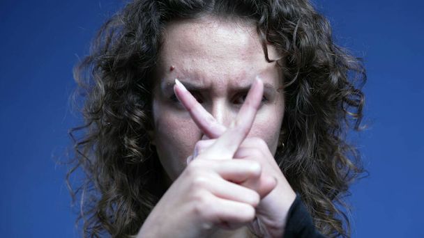 Mujer molesta señalando con el dedo a la cámara, agitando 'NO' en rechazo, primer plano del lenguaje corporal negativo haciendo una "X" con las manos - Foto, Imagen