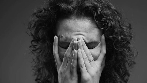 Жінка відчуває сором покриває обличчя рукою з глибоким жаль, людина бореться з відчаєм і проблемною інтроспекцією в інтенсивному чорно-білому - Фото, зображення