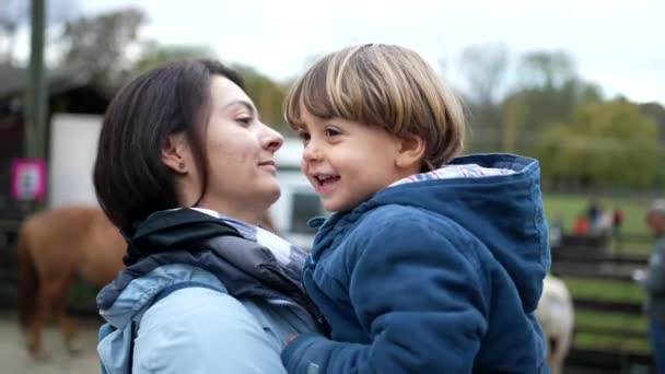 Μητέρα και παιδί δένονται έξω στην αυθεντική πραγματική ζωή στοργική στιγμή φιλιούνται στα χείλη και χορεύουν πλάι-πλάι. Μαμά κρατώντας γιο στην αγκαλιά κατά τη διάρκεια της φθινοπωρινής περιόδου - Πλάνα, βίντεο