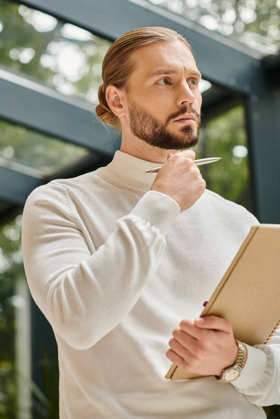 focused good looking architect in white comfy turtleneck with beard holding his paperwork on startup - Photo, Image