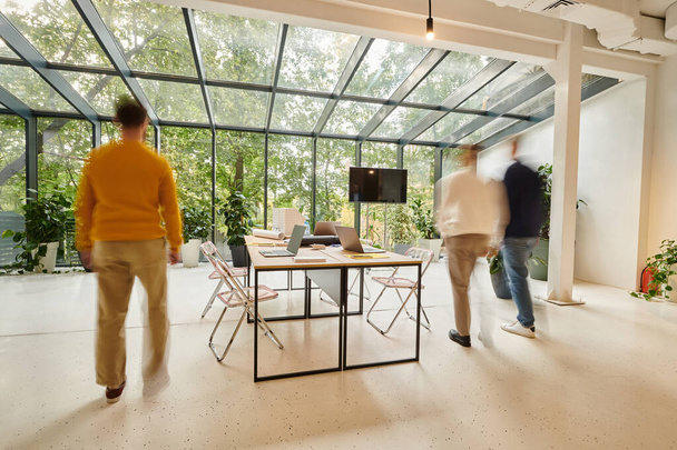 lange belichting foto van zakenmensen in wazige beweging lopen in het kantoor tijdens het werken aan startup - Foto, afbeelding