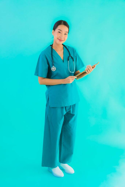 Fotokopi için boş kâğıt tahtası olan güzel Asyalı genç doktor kadın hastane ve klinikteki sağlık hizmetleri konseptinde mavi izole edilmiş arka plan. - Fotoğraf, Görsel
