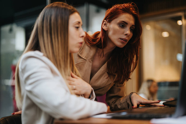 Female, business partners collaborating in a coffee bar, discussing business strategies and data analytics. - Photo, Image