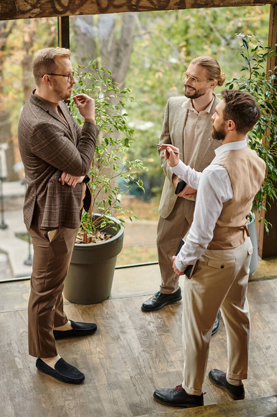 glückliche gut aussehende Unternehmensführer mit Brille in eleganter schicker Kleidung diskutieren ihr Start-up - Foto, Bild