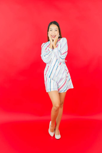 Portrét krásná mladá asijská žena úsměv s mnoha akce na červeném pozadí - Fotografie, Obrázek
