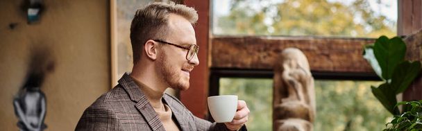 ευχάριστα εξελιγμένο επιχειρηματικό ηγέτη με γυαλιά σε κομψό κοστούμι πίνοντας ζεστό καφέ του, πανό - Φωτογραφία, εικόνα
