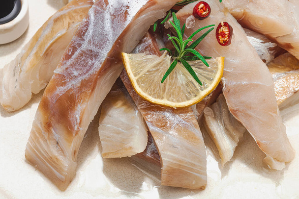 Surový treska evropská (Pollachius virens) filé. Čerstvé ryby pro zdravý životní styl jídla. Citroen, rozmarýn, mořská sůl, chilli, černý pepř. Lehký kámen betonové pozadí, byt ležel, zblízka - Fotografie, Obrázek
