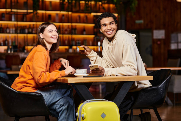 változatos pár miután kávészünet és csinál online vásárlás közelében poggyász a kávézóban, hitelkártya - Fotó, kép