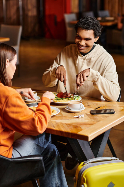 casal diverso almoçando em um restaurante, seus rostos iluminados com alegria enquanto desfrutam de comida saborosa - Foto, Imagem