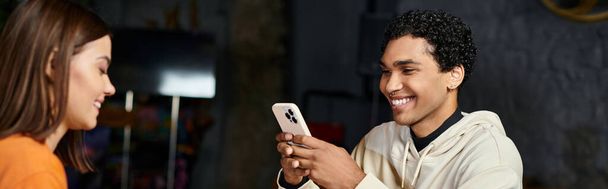 heureux homme noir en utilisant smartphone près de petite amie gaie se trouve en face de lui dans le café, bannière - Photo, image