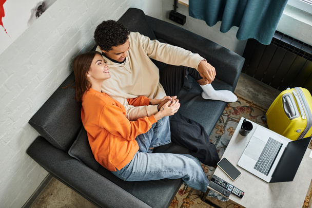 Інтимний накладний знімок міжрасової пари лежить на дивані і дивиться фільм на ноутбук разом - Фото, зображення