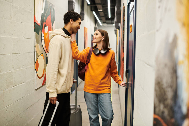 Молодая межрасовая пара, улыбающаяся в хостеле, веселая женщина, открывающая дверь в свою комнату - Фото, изображение