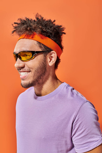 щасливий афроамериканський фалоімітатор в окулярах дивиться далеко на помаранчевий фон, оптимістичний чоловік - Фото, зображення