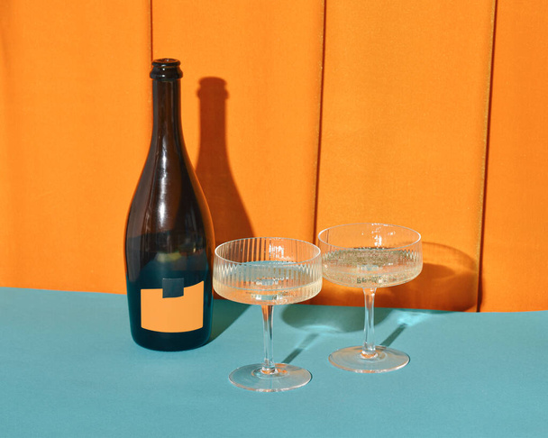 Een fles wijn en twee glazen, warme amber fluwelen draperieën achtergrond, retro stijl champagne partij.  - Foto, afbeelding